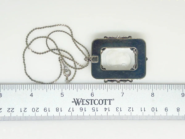 Encased on a silver rectangular frame, this clear rectangular glass pendant is bezel set and exudes timeless charm;It is mounted in a silver rectangular frame adorned with a garland. Measuring 1.75 inches in height and 1.25 inches across, it is a substantial piece that will make a statement. 