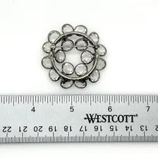 A circular mid-century clear rhinestone brooch resting next to a Westcott wooden ruler to clearly demonstrate the exact diameter in inches