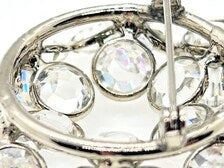 The reverse side of a vintage silver-tone rhinestone brooch displaying the functioning safety pin clasp, and open-back stone settings.