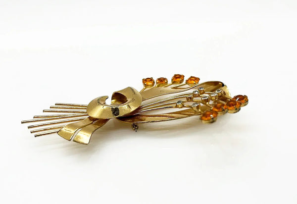 This is a massive Coro Sterling Floral Spray &amp; Ribbon Design brooch. Get mesmerized by the splendor of this vintage brooch, measuring just under 4 inches. The bouquet, intricately designed with a bow, boasts of four gold-toned lines adorned with round, citrine-orange stones of varying sizes.