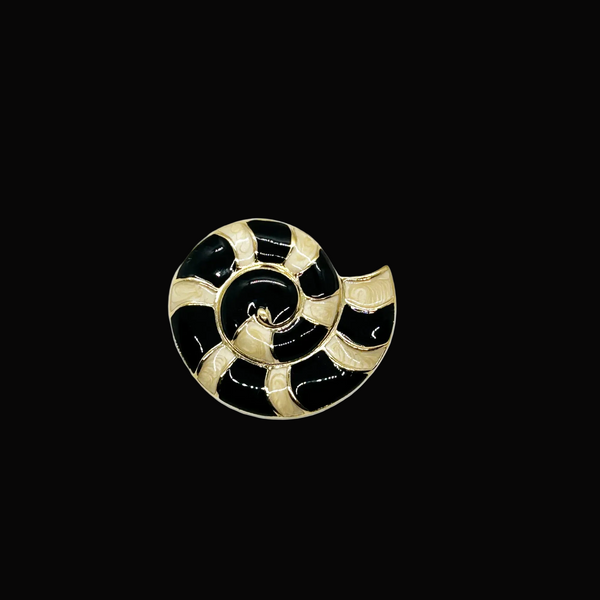 This stunning Trifari brooch captures the elegance of Art Deco design with its spiral seashell silhouette. Crafted in gold-tone metal, it features striking black enamel paired with creamy golden-sand enamel in a sophisticated moire finish.