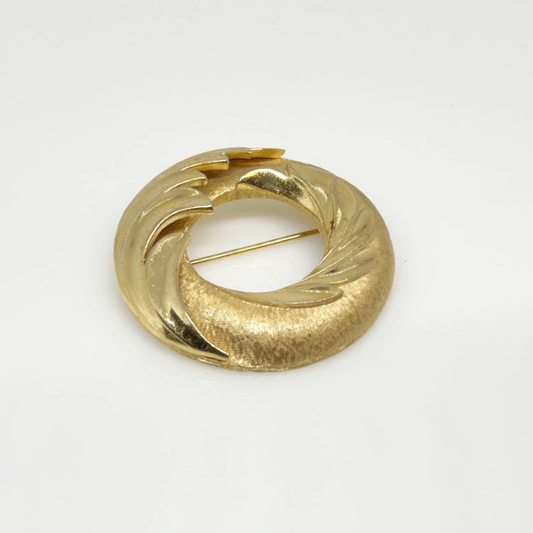 &nbsp;This Crown Trifari brooch combines smooth and textured finishes across two layers, featuring an elegant abstract wave design. A timeless addition to any collection, it’s perfect for making a lasting impression in your wardrobe. Measuring 1.75" in diameter and in excellent condition, it offers a substantial feel of quality.