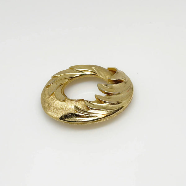 &nbsp;This Crown Trifari brooch combines smooth and textured finishes across two layers, featuring an elegant abstract wave design. A timeless addition to any collection, it’s perfect for making a lasting impression in your wardrobe. Measuring 1.75" in diameter and in excellent condition, it offers a substantial feel of quality.