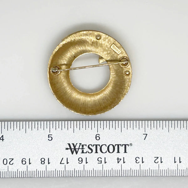 &nbsp;This Crown Trifari brooch combines smooth and textured finishes across two layers, featuring an elegant abstract wave design. A timeless addition to any collection, it’s perfect for making a lasting impression in your wardrobe. Measuring 1.75" in diameter and in excellent condition, it offers a substantial feel of quality.