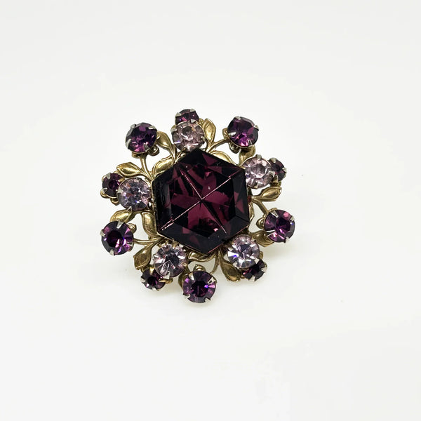 This dazzling brooch features a large octagonal purple stone at its center, surrounded by sparkling lavender and purple round stones. Its two-tiered design highlights the bezel-set centerpiece, making it truly eye-catching. With intricate details that showcase exceptional Czech craftsmanship,