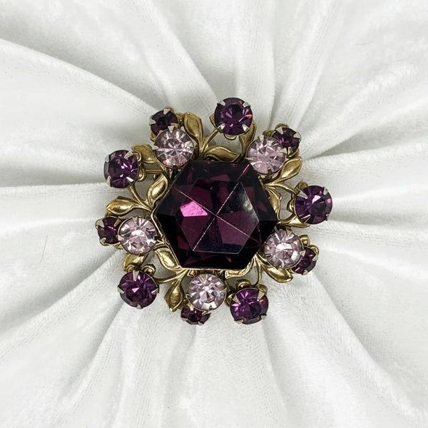 Prepare to turn heads with this audacious 1930s Czech brooch that refuses to blend in. A commanding octagonal amethyst stone commands the center stage, flanked by a constellation of lavender and purple brilliants that catch light from every angle. 