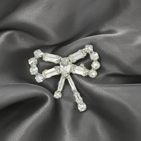 Enhance any outfit with this delicate and exquisite Tiny Rhinestone Vintage Bow Brooch. With its stunning baguette and round stones, hand-set in a sleek frame, this brooch adds a touch of glamour that surpasses what the camera can capture