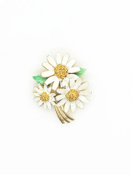 This is a cheerful vintage daisy brooch with enameled petals and a domed golden rhinestone center. It measures 2" long and is in good condition.
