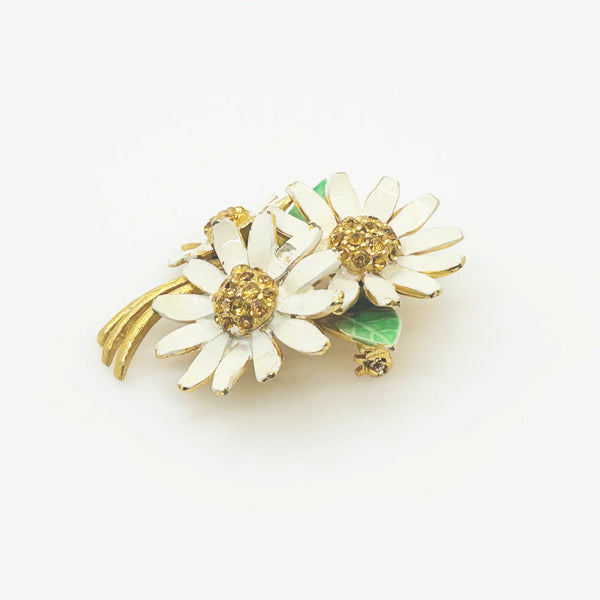This is a cheerful vintage daisy brooch with enameled petals and a domed golden rhinestone center. It measures 2" long and is in good condition.