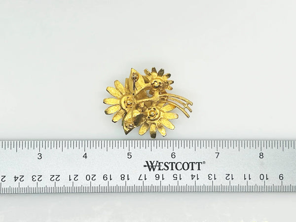 This is a cheerful vintage daisy brooch with enameled petals and a domed golden rhinestone center. It measures 2" long and is in good condition.