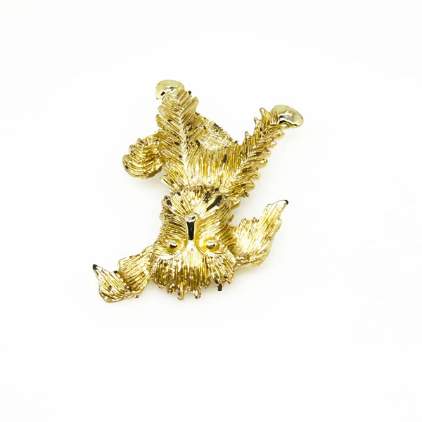 This charming vintage brooch depicts a playful dog caught mid-scratch, its attentive ear perked as if alert to intriguing sounds. The finely textured fur and detailed paws and eyes add refined character. Measuring 1.75", this piece remains in excellent condition, perfect for adding a touch of elegant whimsy to any ensemble. It's a delightful find for any animal lover or someone who appreciates unique, vintage jewelry.
