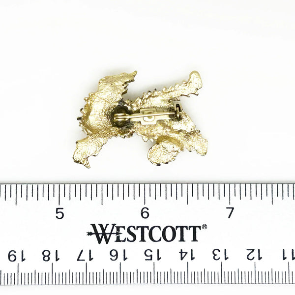 This charming vintage brooch depicts a playful dog caught mid-scratch, its attentive ear perked as if alert to intriguing sounds. The finely textured fur and detailed paws and eyes add refined character. Measuring 1.75", this piece remains in excellent condition, perfect for adding a touch of elegant whimsy to any ensemble. It's a delightful find for any animal lover or someone who appreciates unique, vintage jewelry.
