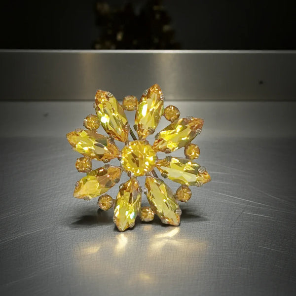 On offer is this antique brooch set with sparkling faceted and open back golden marquise stones, centered around a matching round stone. There are smaller round stones set in between the marquise stones. The open back setting really lends itself to a rich and sparkling effect. 