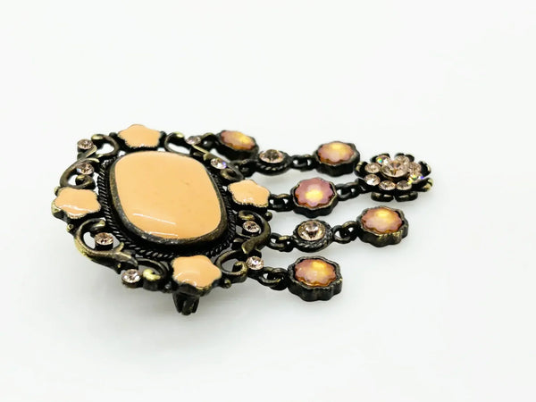 Level up your vintage jewelry collection with this stunning coral-hued brooch that captures timeless elegance. The piece showcases a luminous pale melon-orange centerstone framed by delicate star-shaped accents and peachy rhinestones that catch the light beautifully.