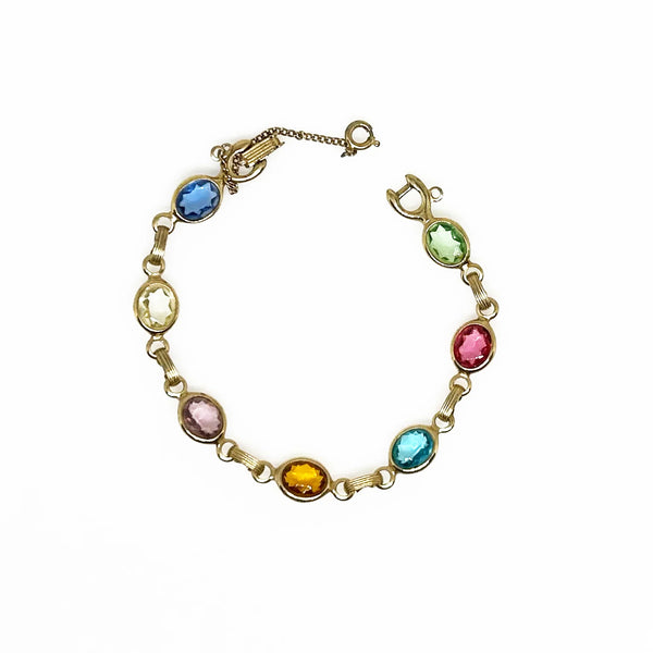 This lovely vintage bracelet is made by Emmons. It’s crafted with seven faceted oval clear bezel set stones. The colors of these stones are pale green, pink, aqua blue, citrine, light purple, pale yellow, and medium blue.