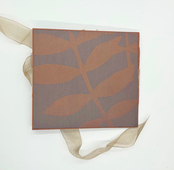 Handmade autumn mini scrapbook album featuring a green and brown plaid pattern, orange paper cover, decorative fall leaves, and a large golden ribbon bow
