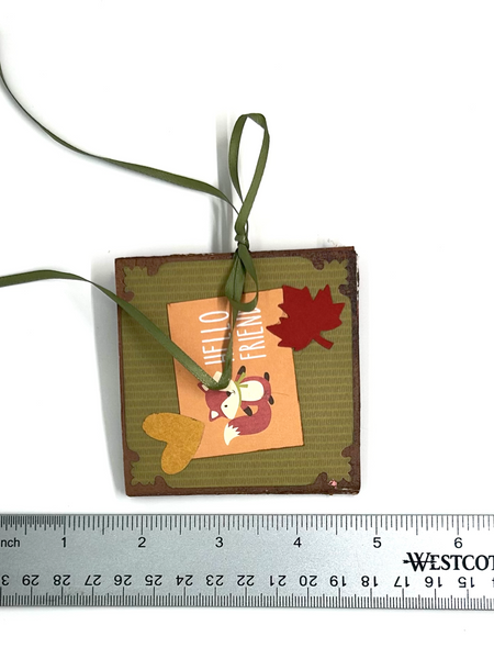Handmade autumn mini scrapbook album featuring a green and brown plaid pattern, orange paper cover, decorative fall leaves, and a large golden ribbon bow