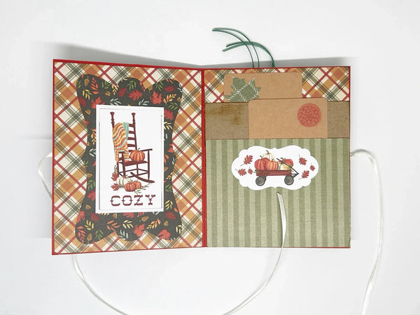 This one-of-a-kind handmade mini album captures the essence of fall – the most wonderful season! Showcasing rich shades of pumpkin, loden green, and cinnamon, it measures 4.75" tall by 3.75" wide and is secured with a soft off-white ribbon. 