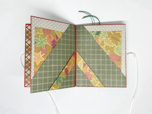 This one-of-a-kind handmade mini album captures the essence of fall – the most wonderful season! Showcasing rich shades of pumpkin, loden green, and cinnamon, it measures 4.75" tall by 3.75" wide and is secured with a soft off-white ribbon. 