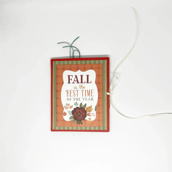 This one-of-a-kind handmade mini album captures the essence of fall – the most wonderful season! Showcasing rich shades of pumpkin, loden green, and cinnamon, it measures 4.75" tall by 3.75" wide and is secured with a soft off-white ribbon. 