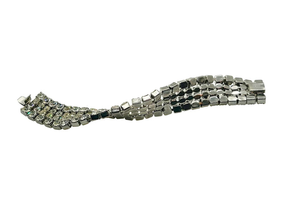 This vintage rhinestone bracelet provides an elegant touch to any ensemble. Featuring four rows of meticulously prong-set rhinestones, it measures approximately 7 inches in length and 0.75 inches in width. 