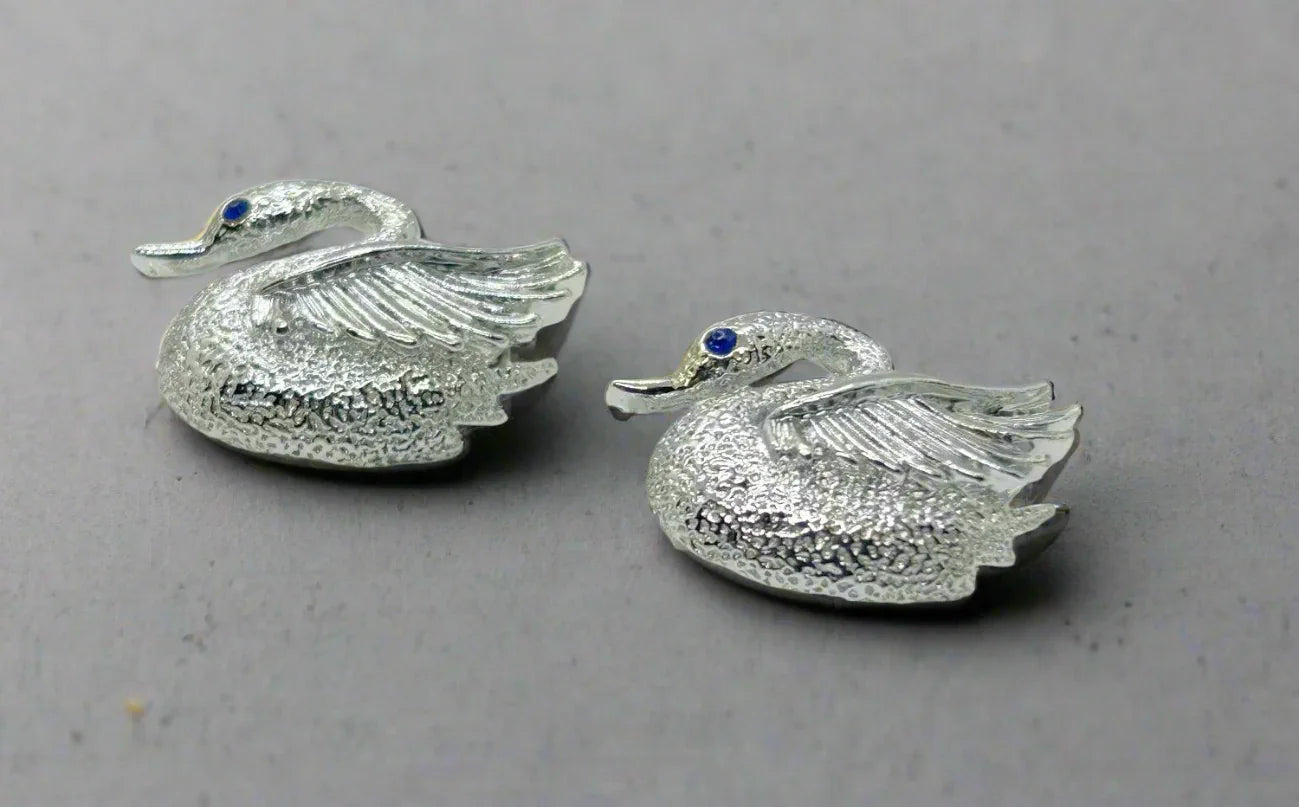 Indulge in the opulence of these exquisitely crafted pins adorned with intricate details and signed by the renowned Gerry's. Made from sleek silver tone metal, each pin boasts a textured body and lustrous wings. Mesmerizing bright blue stones serve as their striking eyes, while measuring just over 1" wide. In impeccable condition, these pins radiate elegance and sophistication.