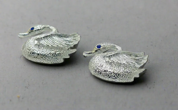 Indulge in the opulence of these exquisitely crafted pins adorned with intricate details and signed by the renowned Gerry's. Made from sleek silver tone metal, each pin boasts a textured body and lustrous wings. Mesmerizing bright blue stones serve as their striking eyes, while measuring just over 1" wide. In impeccable condition, these pins radiate elegance and sophistication.