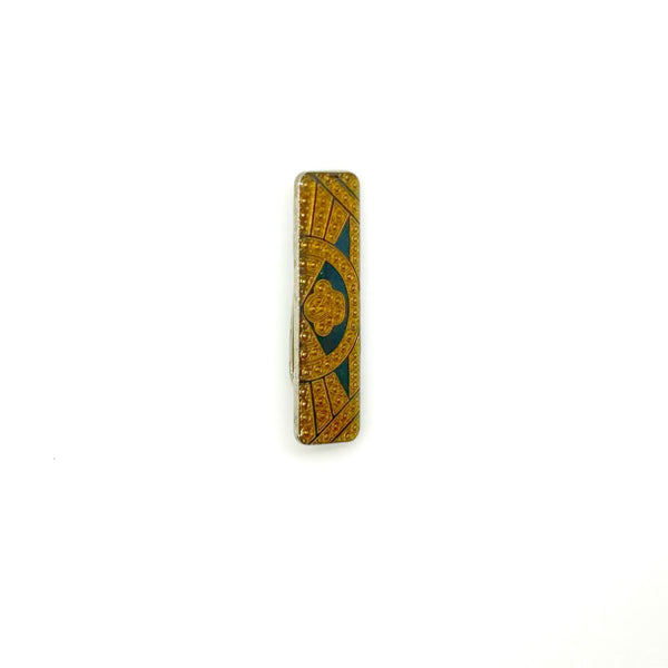 A vintage rectangular Art Deco revival bar brooch in the Pierre Bex style, featuring textured gold-tone metal sunburst rays, dark enamel details, and a central floral cloud medallion against a solid white background