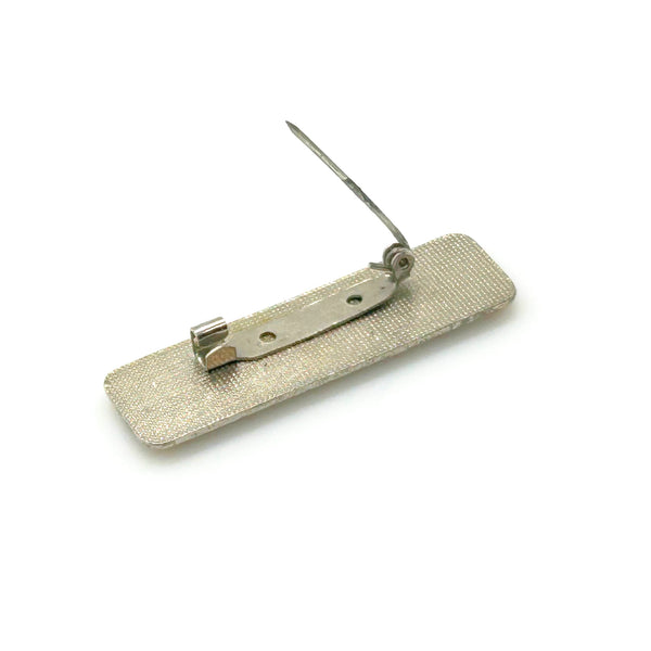A vintage rectangular Art Deco revival bar brooch in the Pierre Bex style, featuring textured gold-tone metal sunburst rays, dark enamel details, and a central floral cloud medallion against a solid white background