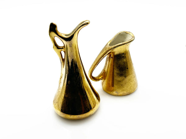 These lovely Victoria HU miniature pitchers are a wonderful addition to any vintage collection. This matched pair, produced in Czechoslovakia during the 1919-1940s era, embodies the refined aesthetic of Art Deco and Hollywood Regency design.