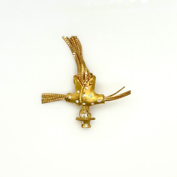 Detailed close-up of a vintage figural scarecrow brooch showing the textured metal patterns, embedded clear chaton rhinestones, and individual strands of fluid herringbone chain hanging from the tors