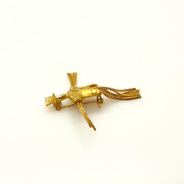 Detailed close-up of a vintage figural scarecrow brooch showing the textured metal patterns, embedded clear chaton rhinestones, and individual strands of fluid herringbone chain hanging from the tors