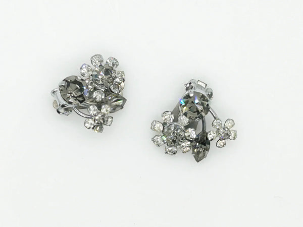 These vintage Sparkling Gray Austria Rhinestone Earrings captivate with their dazzling brilliance. Featuring a mix of gray and clear rhinestones expertly cut in marquise and round shapes, their intricate arrangement forms an elegant, eye-catching pattern