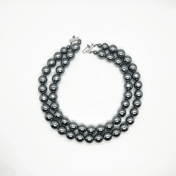 Get ready to make a statement with this stunning Vintage Double Strand of Luminous Smoky Faux Pearls Necklace! The glossy, rich gunmetal color adds a touch of elegance without being too flashy.