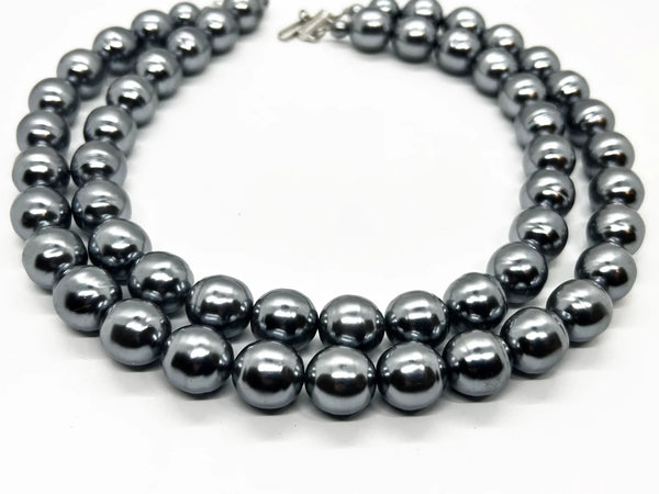Get ready to make a statement with this stunning Vintage Double Strand of Luminous Smoky Faux Pearls Necklace! The glossy, rich gunmetal color adds a touch of elegance without being too flashy.