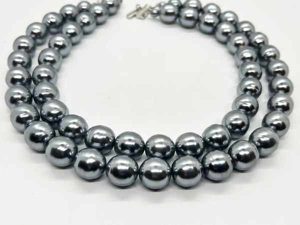 Get ready to make a statement with this stunning Vintage Double Strand of Luminous Smoky Faux Pearls Necklace! The glossy, rich gunmetal color adds a touch of elegance without being too flashy.