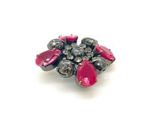 Vintage costume jewelry brooch pin featuring a central rhinestone cluster encircled by a halo of clear crystals, with alternating pear-cut pink faux rubies and round faceted gunmetal black stones in a dark metallic prong setting.