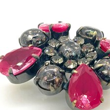 Vintage costume jewelry brooch pin featuring a central rhinestone cluster encircled by a halo of clear crystals, with alternating pear-cut pink faux rubies and round faceted gunmetal black stones in a dark metallic prong setting.