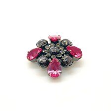 Vintage costume jewelry brooch pin featuring a central rhinestone cluster encircled by a halo of clear crystals, with alternating pear-cut pink faux rubies and round faceted gunmetal black stones in a dark metallic prong setting.