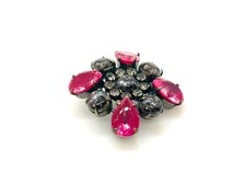 Vintage costume jewelry brooch pin featuring a central rhinestone cluster encircled by a halo of clear crystals, with alternating pear-cut pink faux rubies and round faceted gunmetal black stones in a dark metallic prong setting.