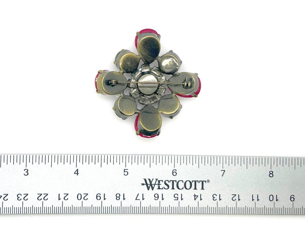 Vintage costume jewelry brooch pin featuring a central rhinestone cluster encircled by a halo of clear crystals, with alternating pear-cut pink faux rubies and round faceted gunmetal black stones in a dark metallic prong setting.