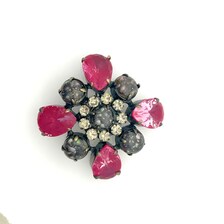 Vintage costume jewelry brooch pin featuring a central rhinestone cluster encircled by a halo of clear crystals, with alternating pear-cut pink faux rubies and round faceted gunmetal black stones in a dark metallic prong setting.