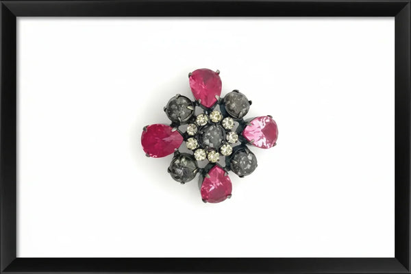 Vintage costume jewelry brooch pin featuring a central rhinestone cluster encircled by a halo of clear crystals, with alternating pear-cut pink faux rubies and round faceted gunmetal black stones in a dark metallic prong setting.
