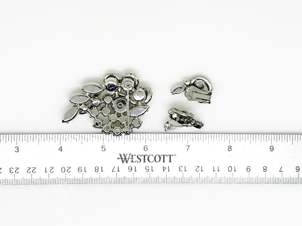 This dazzling set features gray and clear rhinestones that catch the light just right! Swirling marquise and round stones are playfully topped with sparkling pave stones, creating a layered sparkle effect. The hinge-back earrings are the perfect match, each standing a charming 1" tall, while the brooch shines at 2.25" long. All pieces are in excellent vintage condition, ready to add a little sparkle to your day