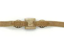 A close-up shot of a vintage gold-toned mesh bracelet, featuring a flexible, textured metal band woven into a mesh pattern.