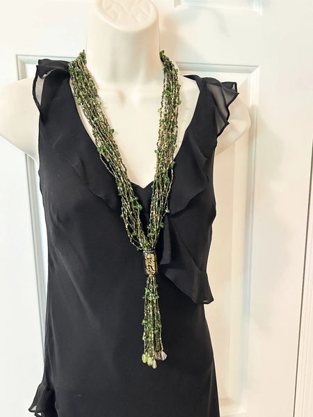 This is a substantial, but easy to wear long 1920s-30s Green Multi Strand Glass Beads Necklace. It made of of thousands of tiny beads in shades of light to deep green. Each bead catches the light and is beautiful. It is anchored by a rectangular green and gold&nbsp; bead which shimmers, introducing a timeless classic in jewelry design.