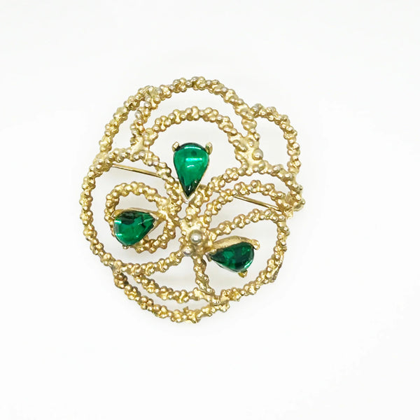 This is an unusual and eye catching vintage Dalshiem brooch. It has textured gold tone metal swirls in an abstract pattern. Teardrop shaped emerald green cabochons add measures additional flair.