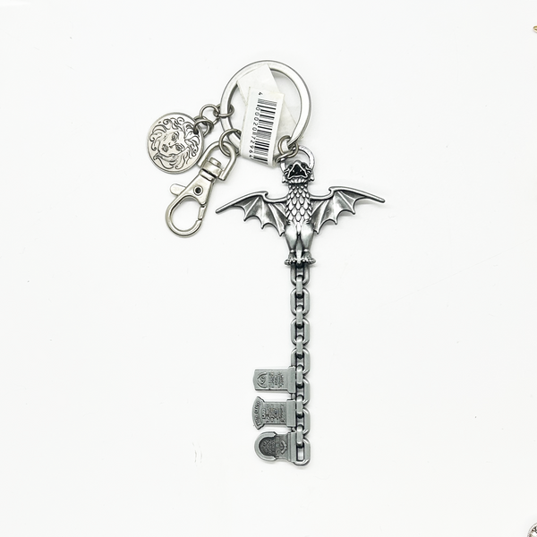 Silver dragon-shaped keychain with attached charms on a white background