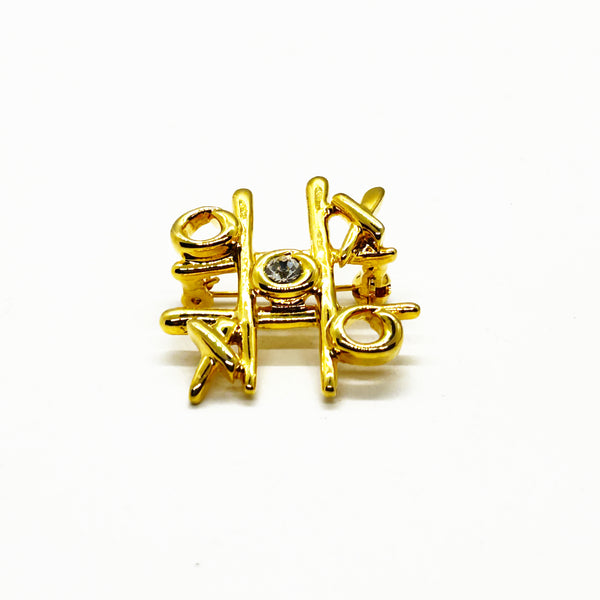 This charming Anne Klein brooch captures the playful spirit of vintage costume jewelry with its clever tic-tac-toe design. Crafted in warm gold tone, the piece features an open-style board complete with X's and O's, crowned by a sparkling clear rhinestone at its center