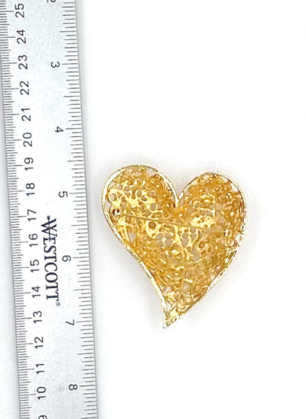 A refined vintage heart brooch that exemplifies mid-century craftsmanship at its finest. The intricate filigree detailing frames an elegant composition of faux pearls in varied forms, while delicate rhinestone accents provide understated luminosity.